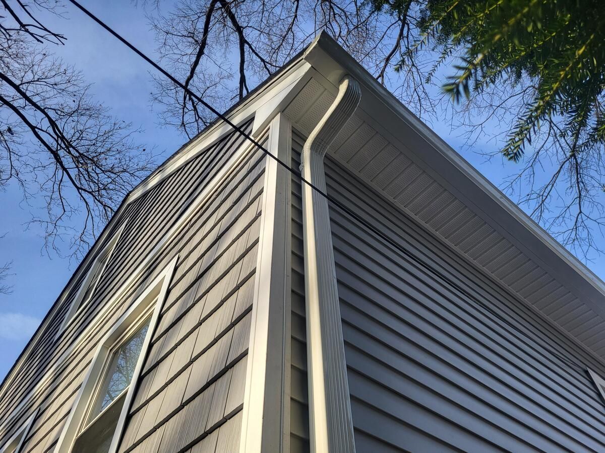 Corner view of a gray house with white trim against a blue sky