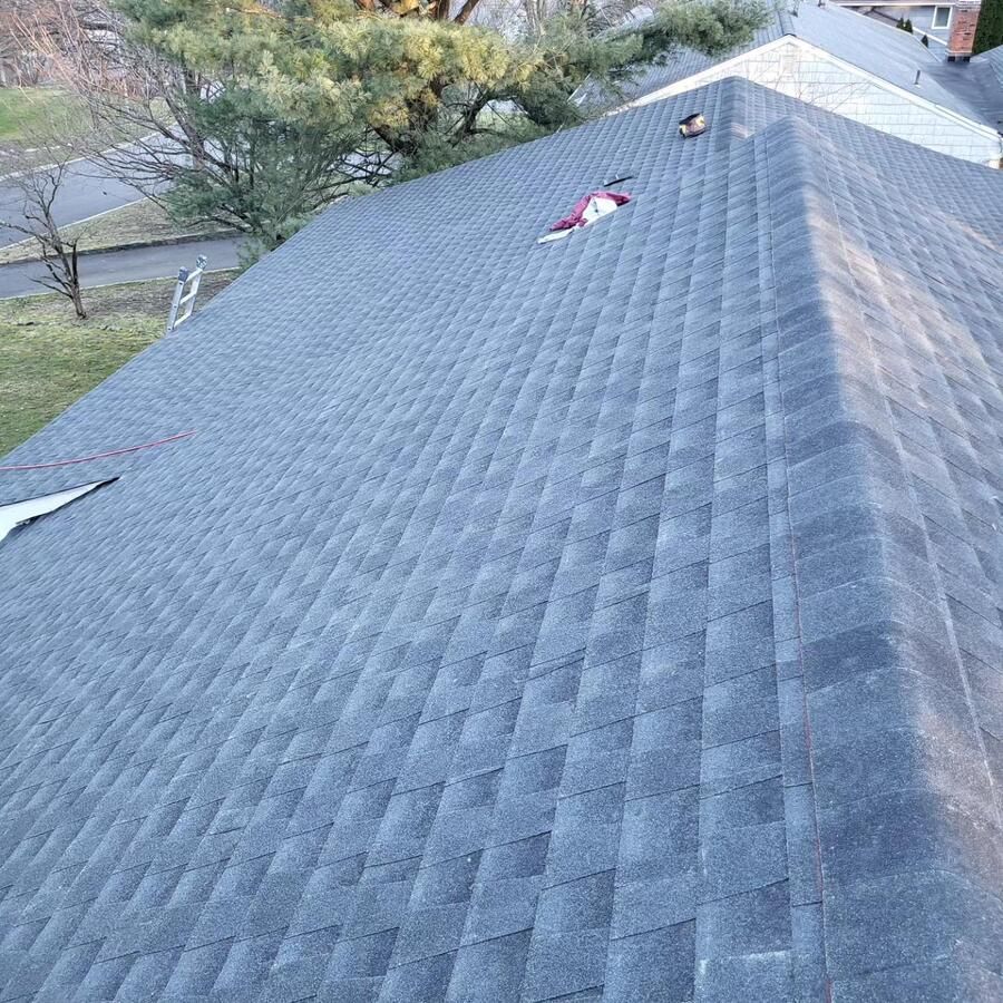 Gray shingled roof with a few damaged spots near the ridge, viewed from above