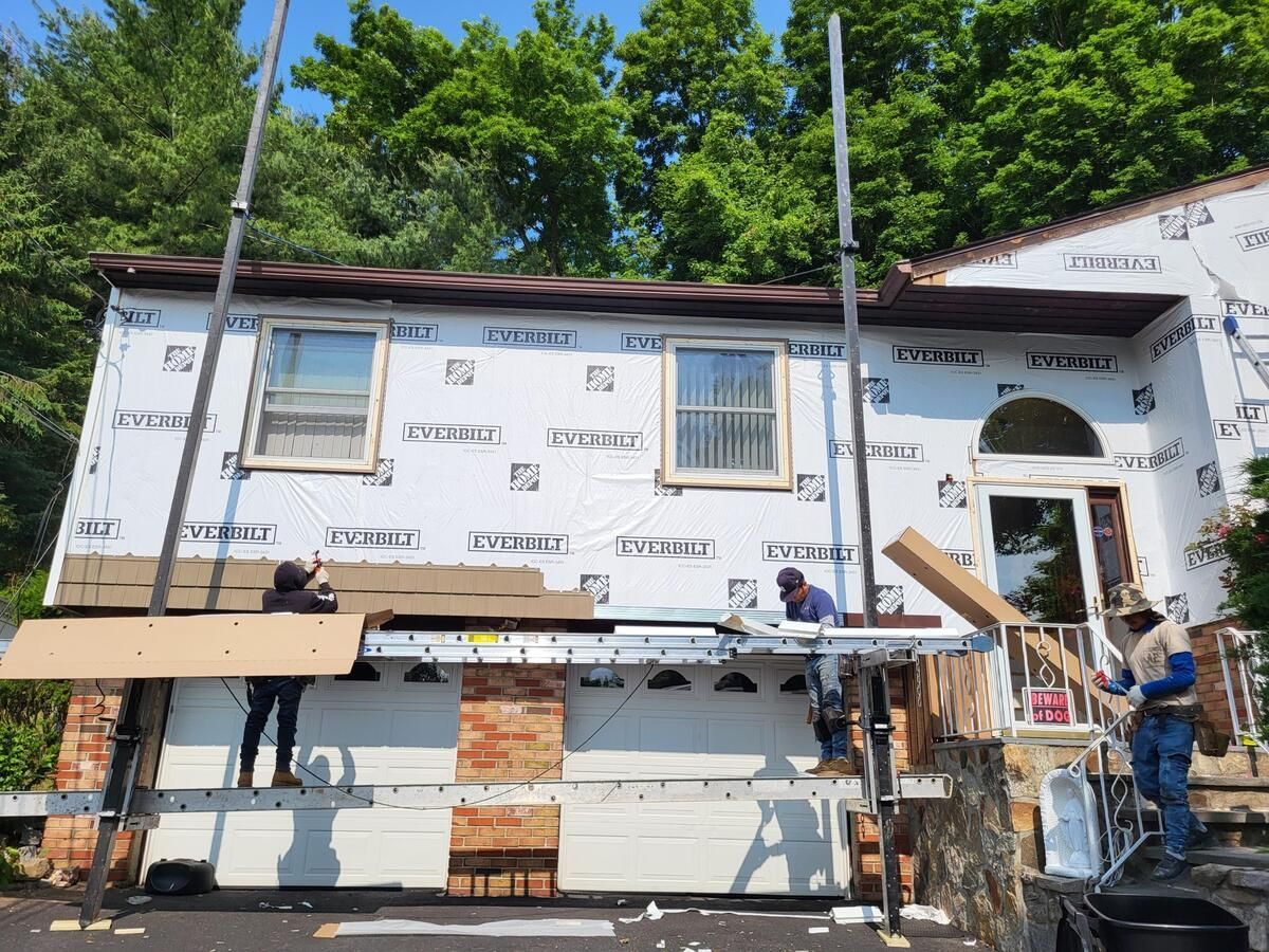 Two-story white house under construction with scaffolding, exposed wood, and workers outside.
