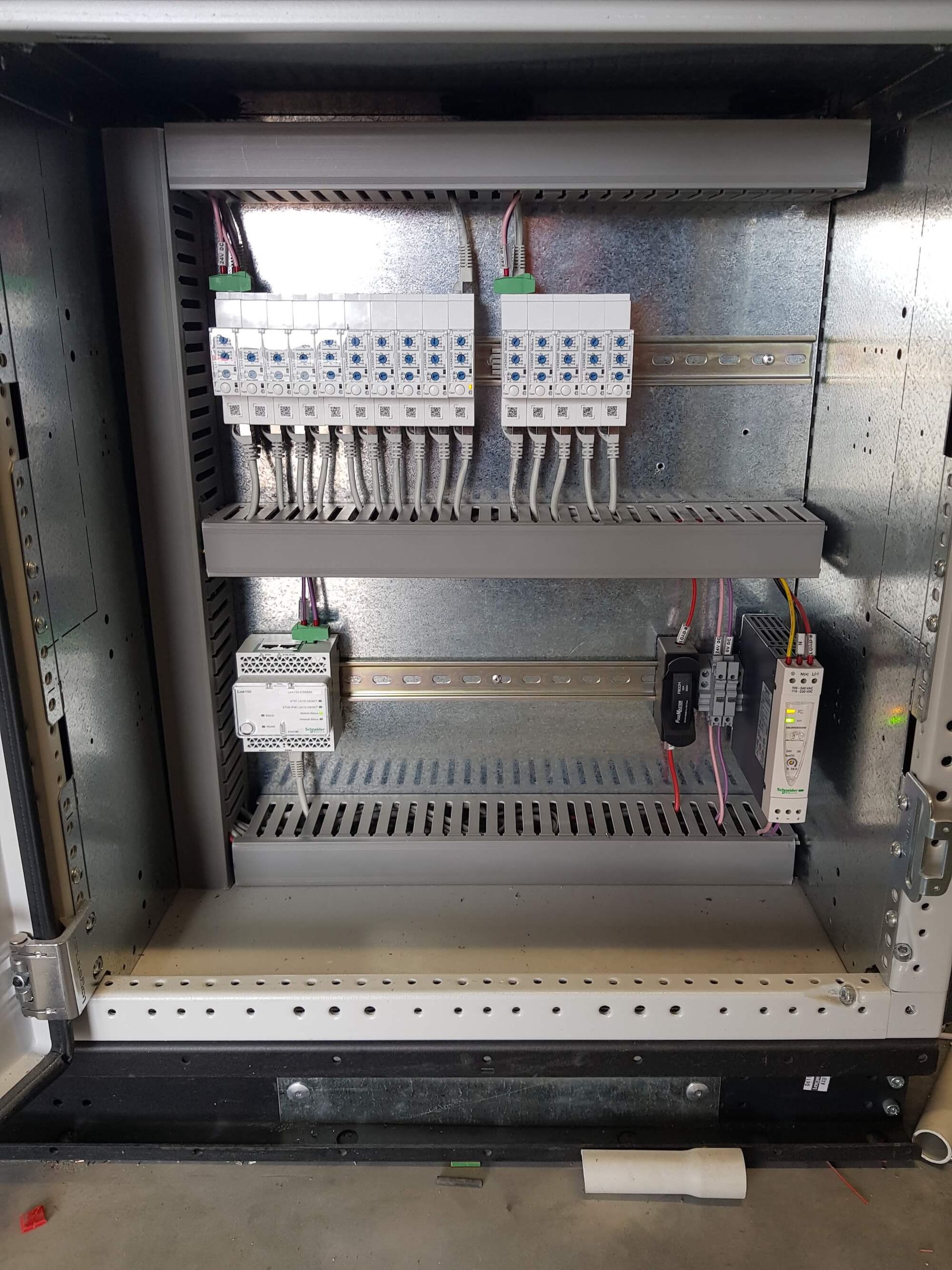Control panel with electrical components, including terminal blocks and relays, mounted inside a metal enclosure.