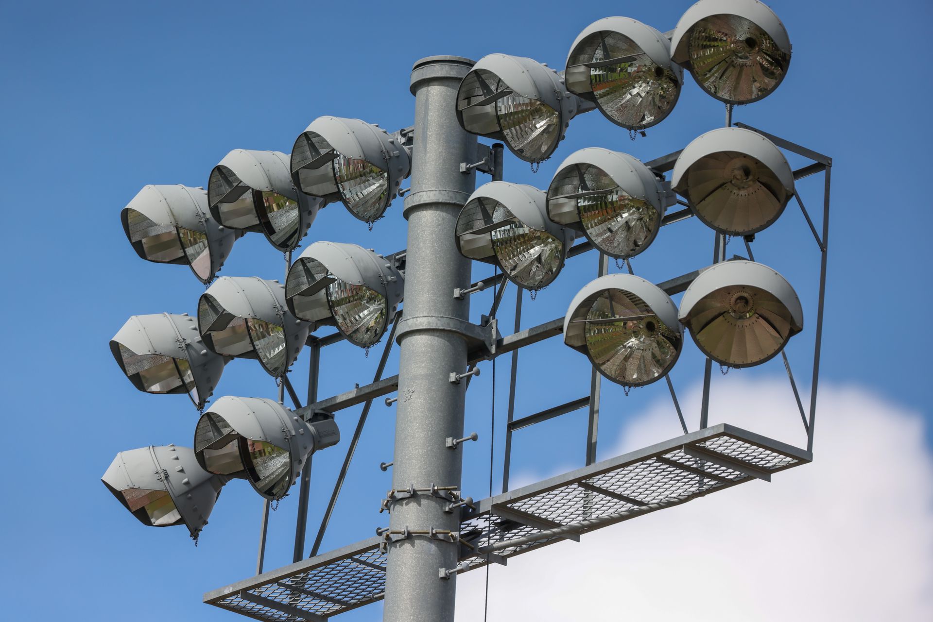 Stadium light over a baseball field with blue sky and puffy clouds in the background.