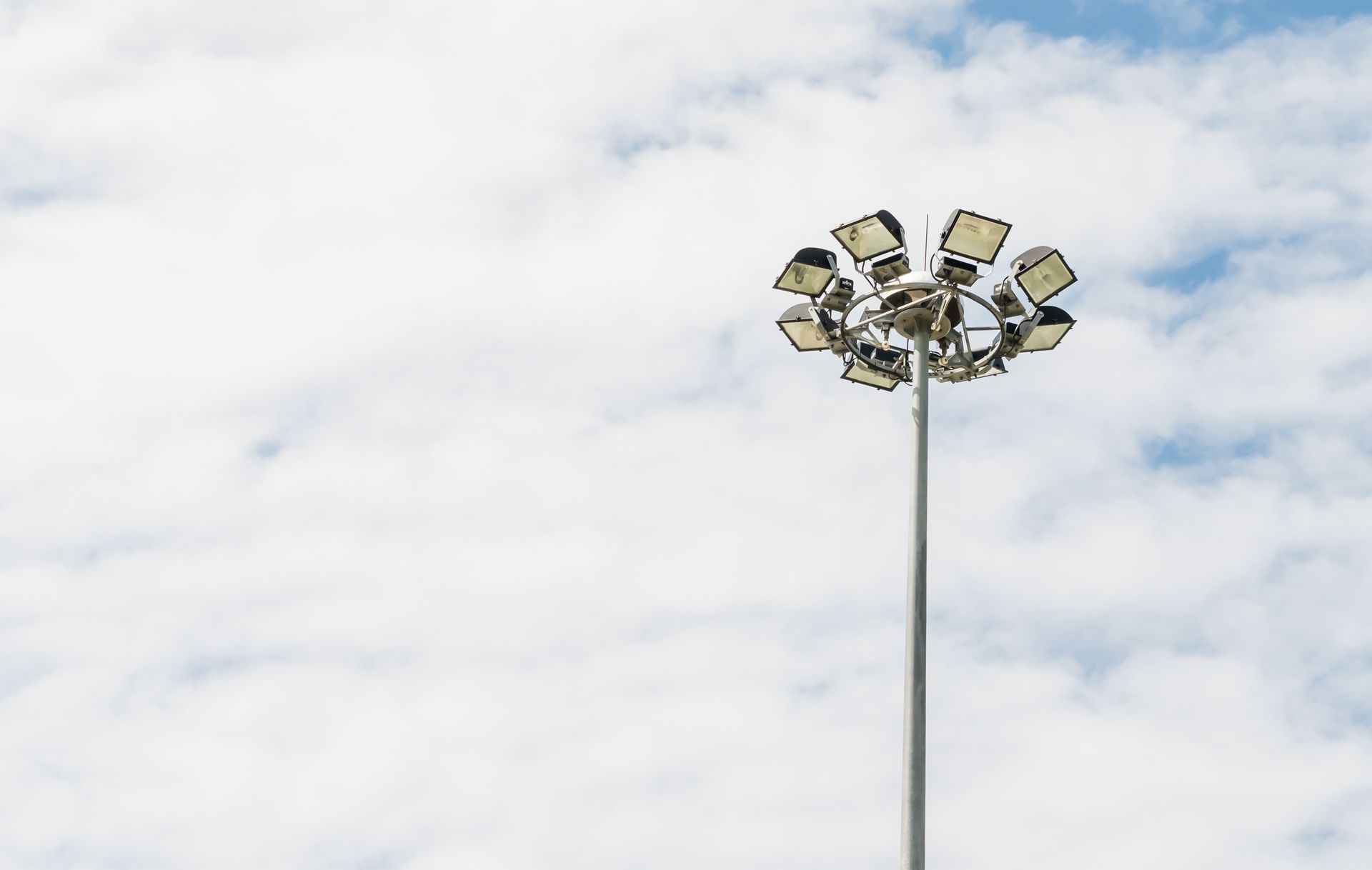 A spotlight tower on a white cloud sky.