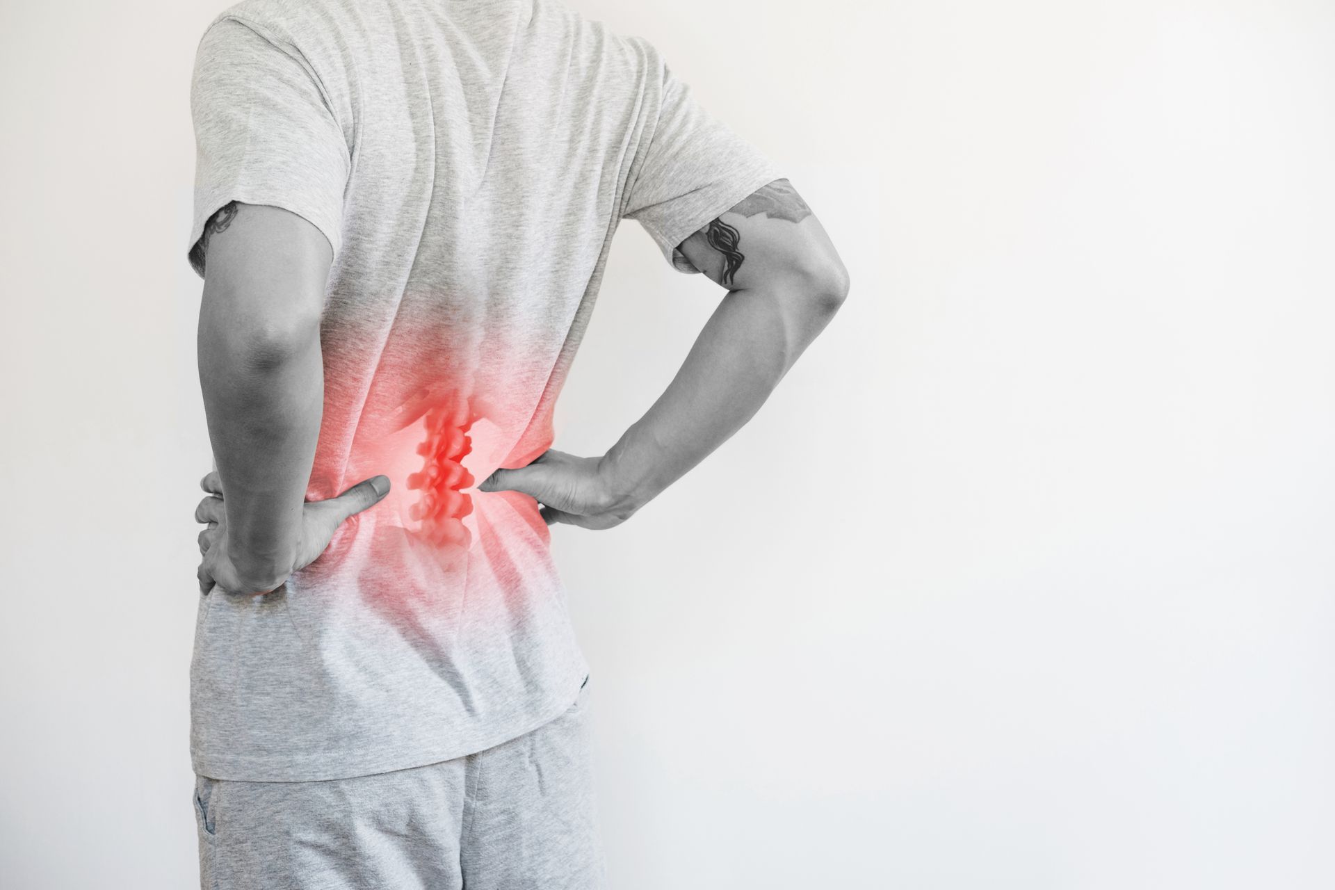 Person clutching lower back with red pain highlight, standing against a white background