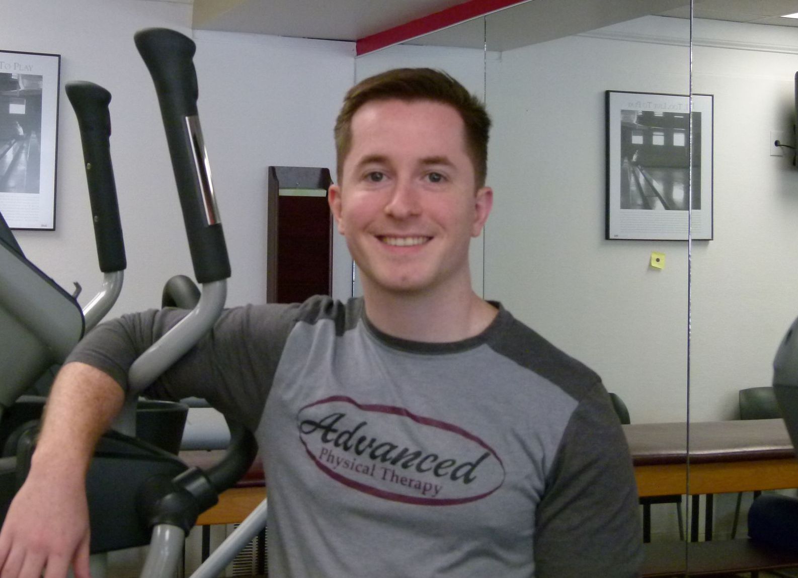 A smiling person in a grey, short-sleeved 
