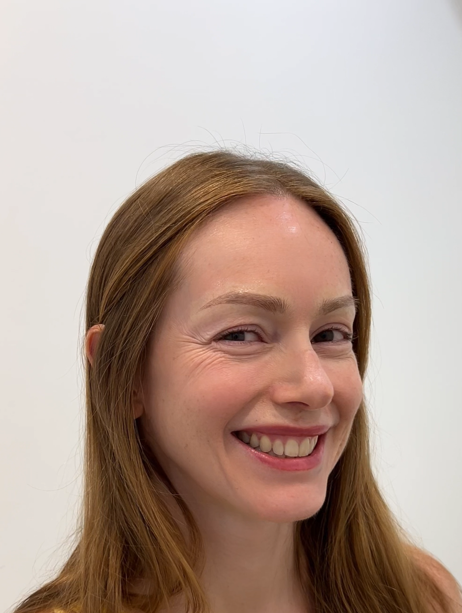 Close-up of a person's eyes and eyebrows; the person partially covered with a white cloth. Dark brown eyebrows and light brown eyes.