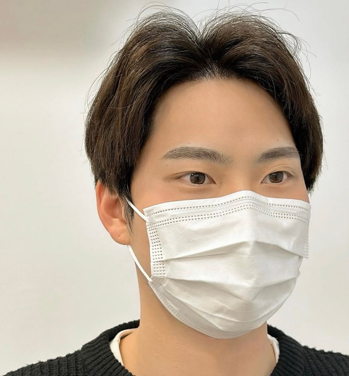 A person's eyes and part of their face peeking from under a white blanket. Brown eyes, eyebrows, and shadow.