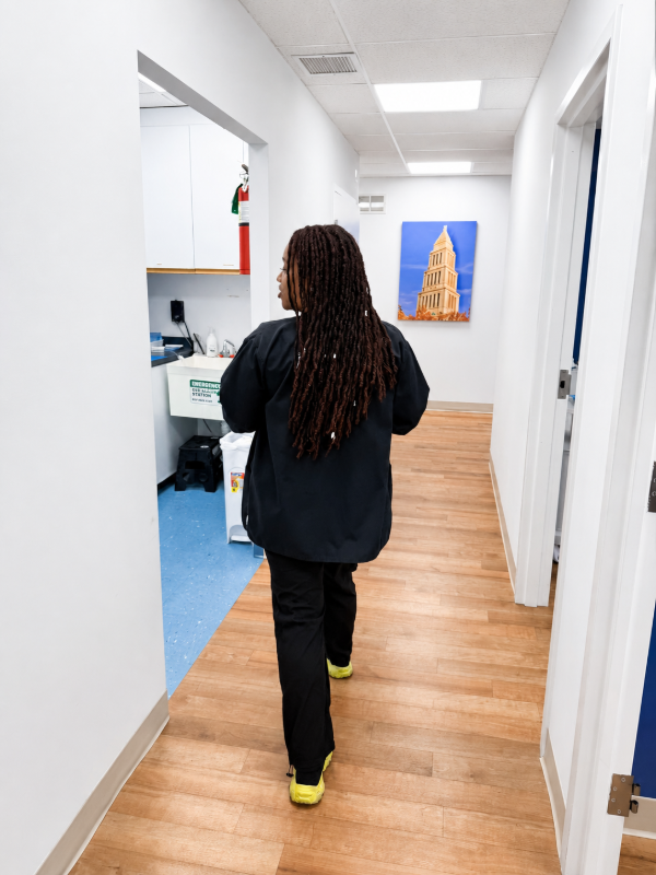 Person walking down a bright hallway toward a blue wall painting.