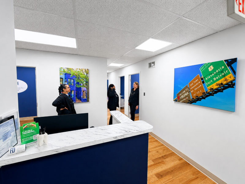 Modern office reception area with blue counter, wall art, and a person standing in the hallway