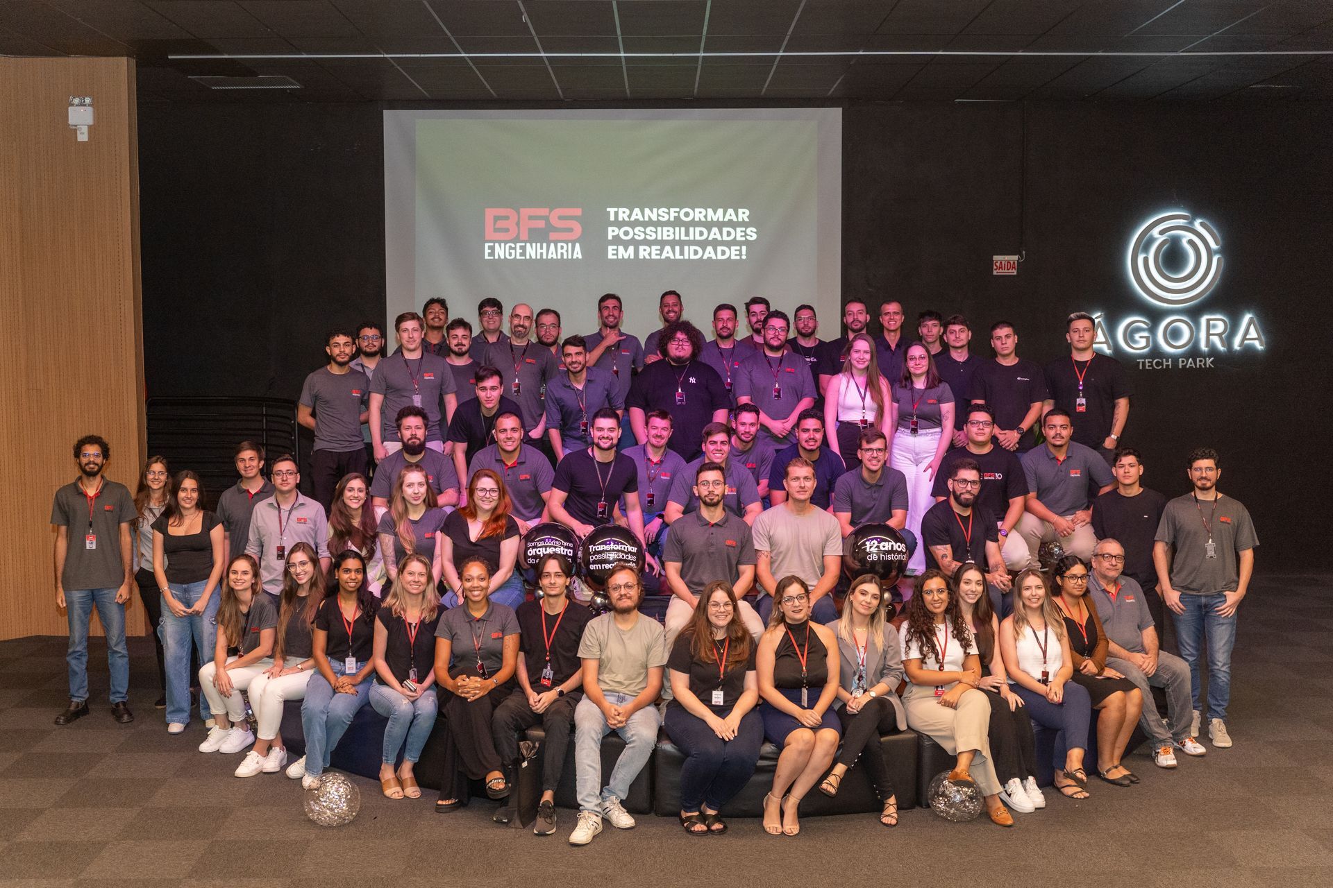 Um grande grupo de pessoas está posando para uma foto em frente a um prédio.
