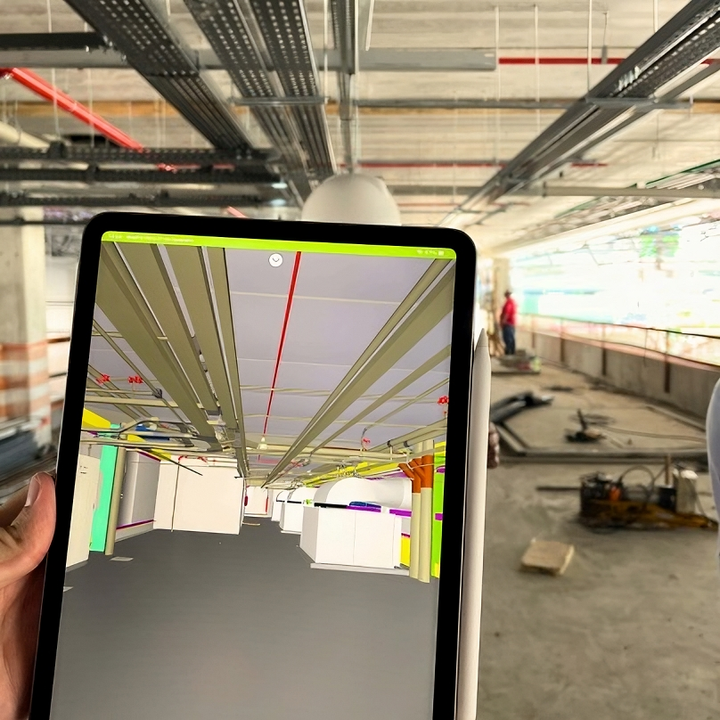 Uma pessoa está segurando um tablet em frente a um prédio em construção