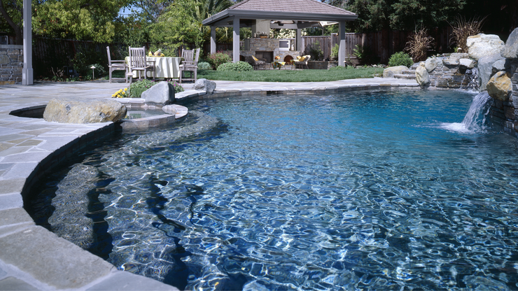 A man is cleaning a swimming pool with a vacuum cleaner.