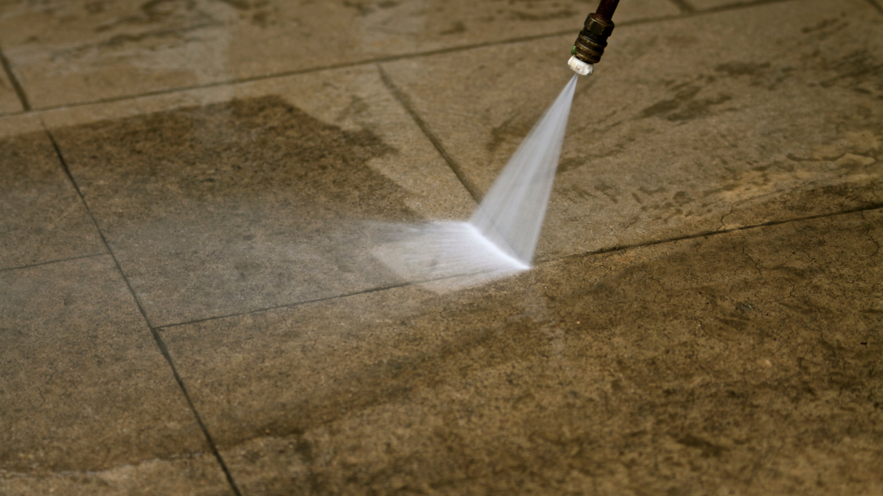 Pressure washer spraying water onto a stone tiled surface.