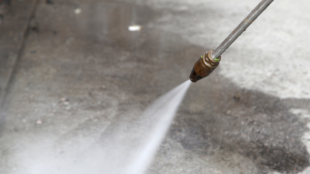 Pressure washer nozzle spraying water onto concrete.