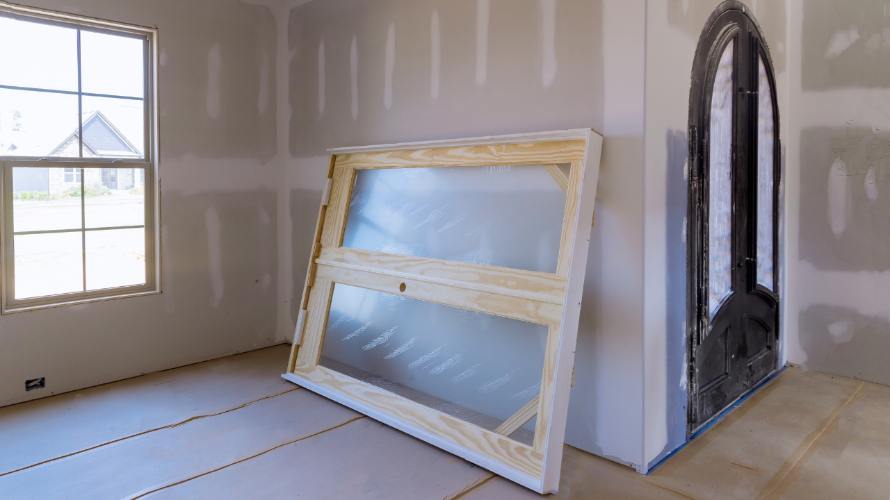 Interior room under construction with window frame leaning against wall.