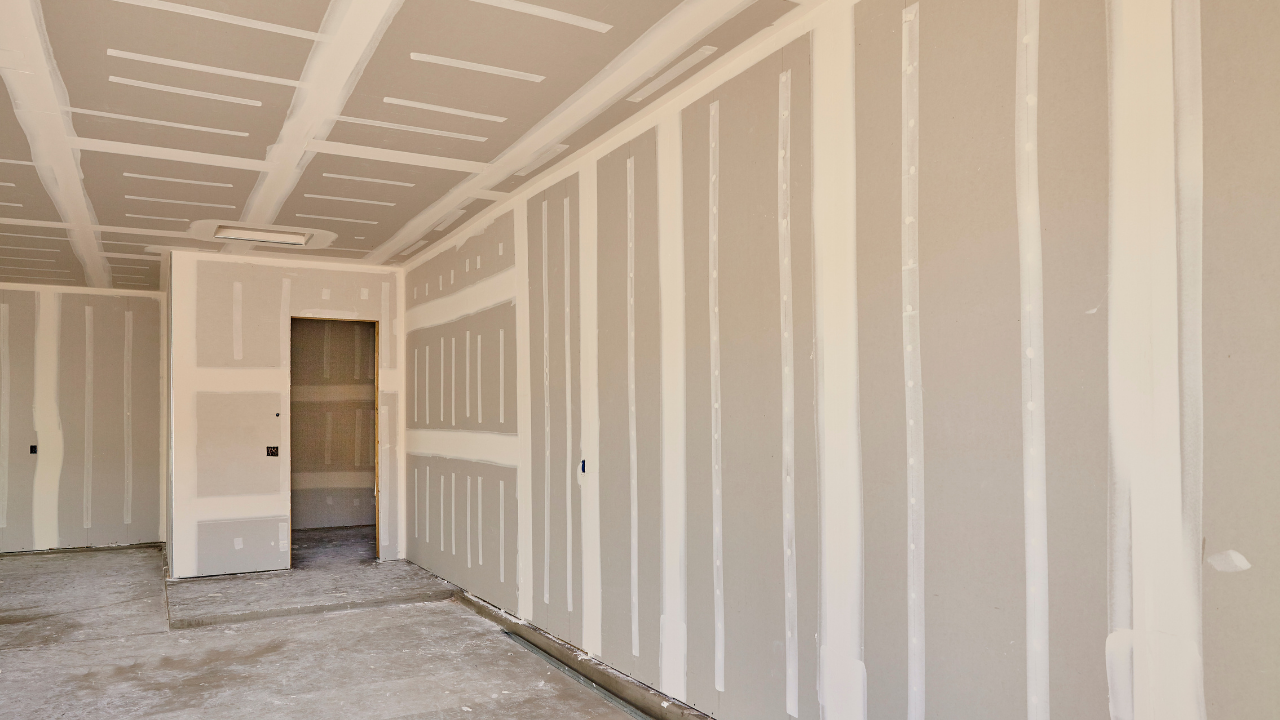 Interior view of room with drywall walls and ceiling, partially constructed, with door frame.
