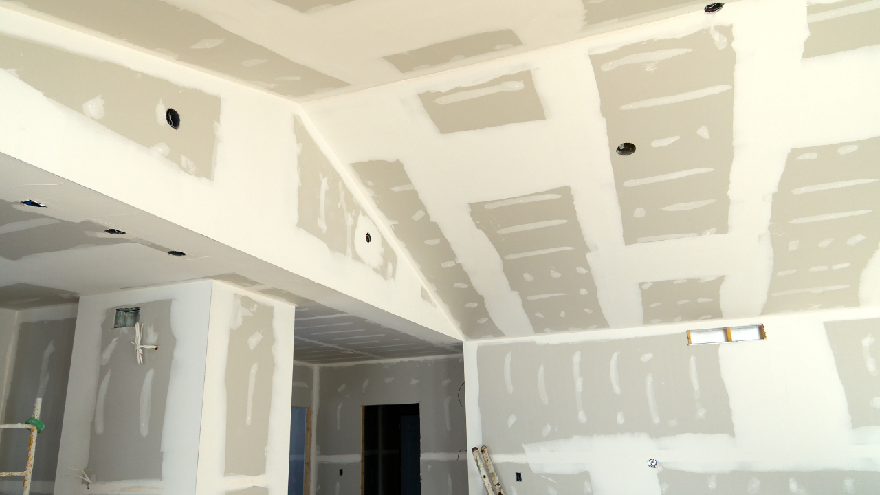 Interior of a room under construction; drywall installation on walls and angled ceiling.