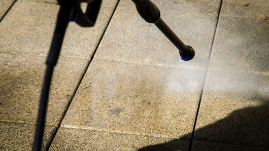 Pressure washer cleaning stone patio. Spraying water and creating mist.