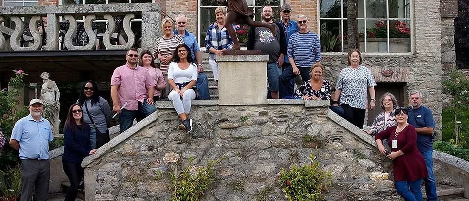 Group of people posing on stone steps in front of a stone building outdoors