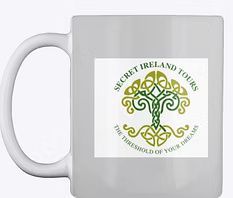White mug with green “Secret Ireland Tours” logo featuring a Celtic tree and “The Threshold of Your Journey” text