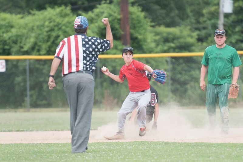Baseball game: player slides, umpire signals safe, another player watches. Outdoor field setting.