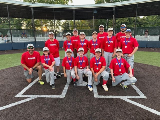 Baseball team in red shirts and hats with medals on the field.