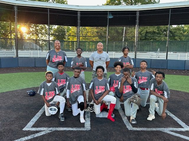Baseball team poses on the field, wearing red and gray jerseys.