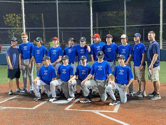 Baseball team in blue shirts and hats posing on a field; some kneeling.