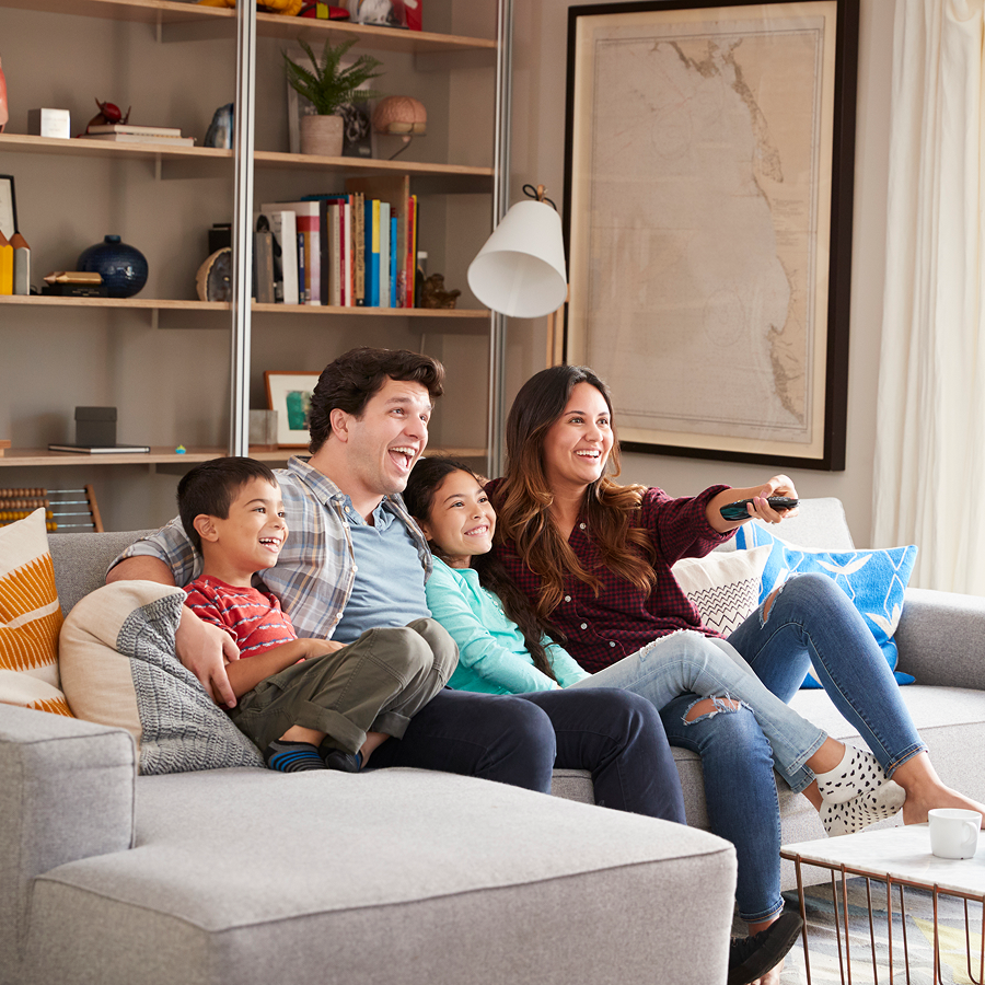 A family is sitting on a couch watching tv.