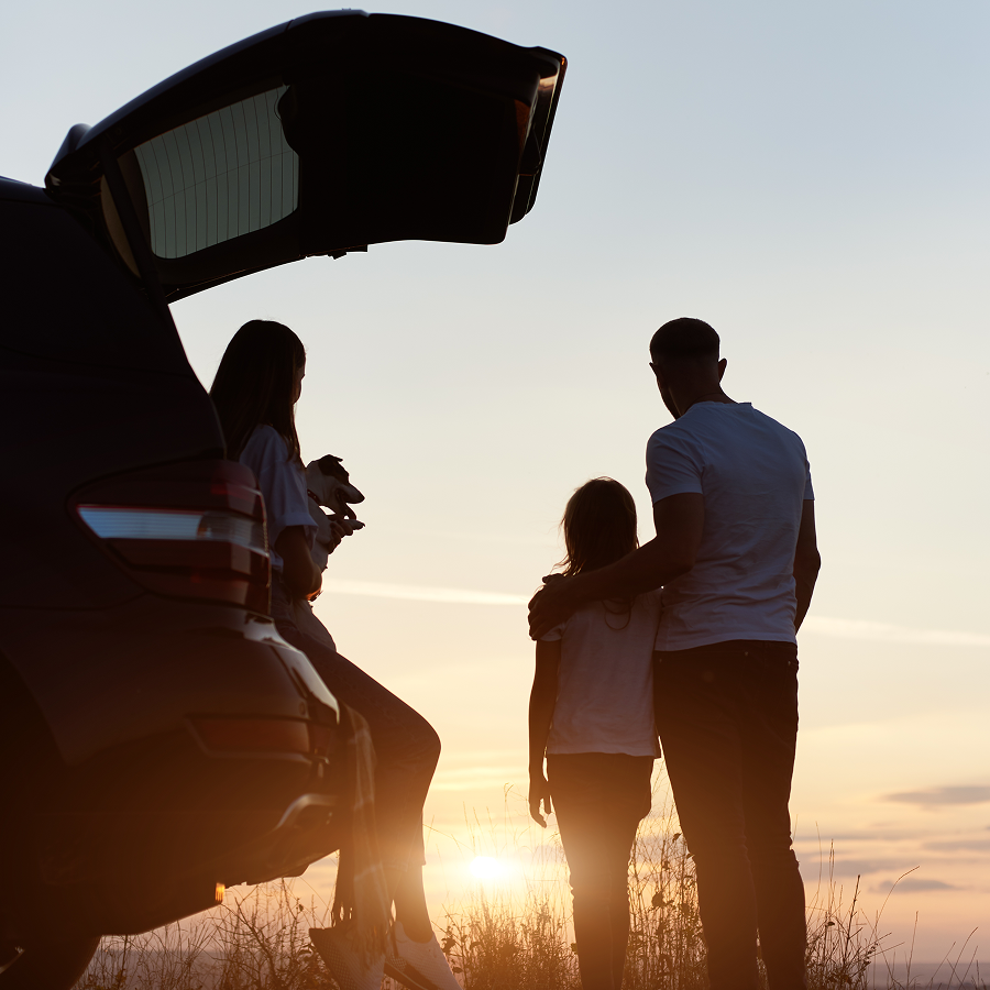 A family is sitting in the back of a car at sunset.