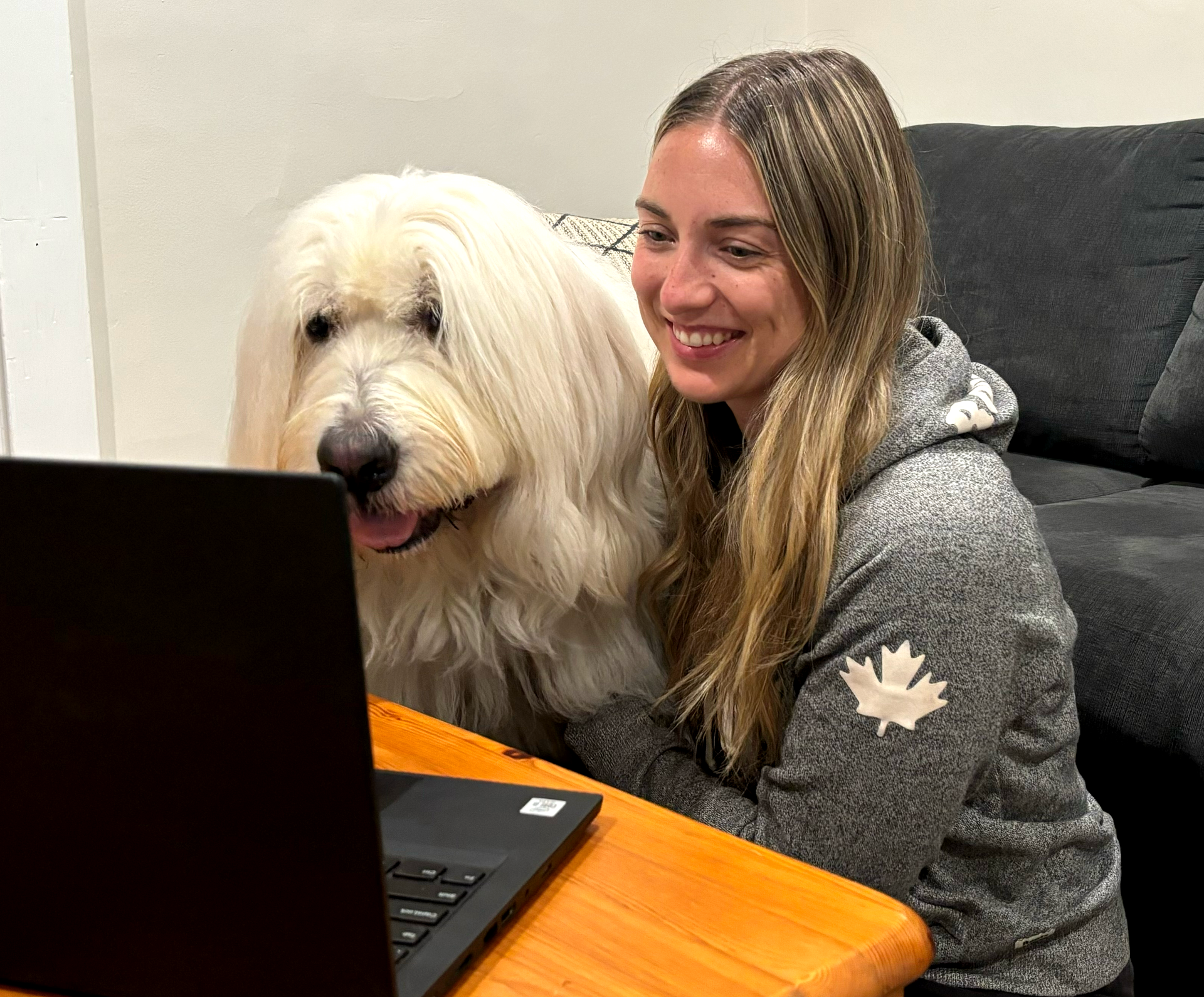 Lady sitting with her dog as they are watching what's on the screen of their laptop together