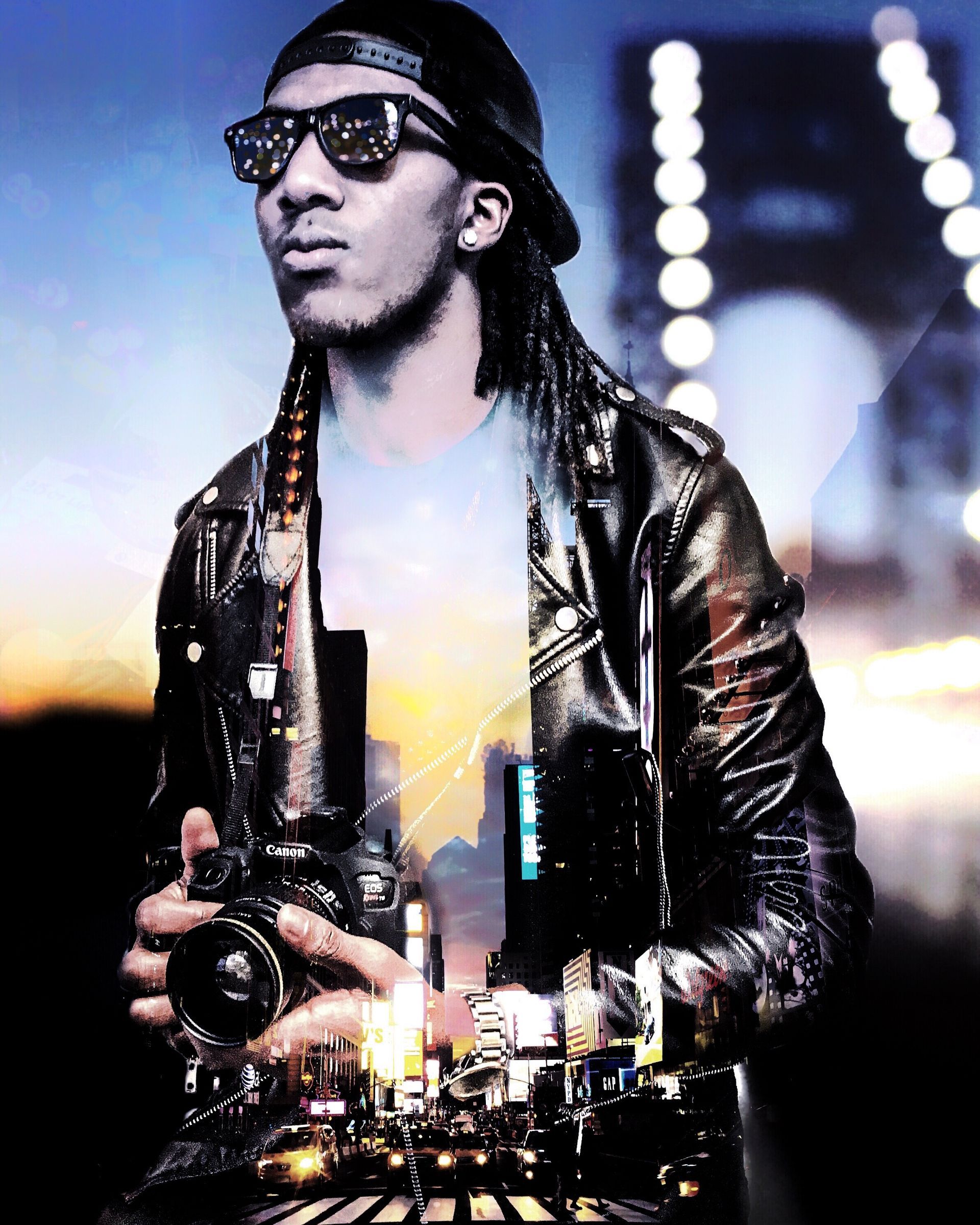 Man in sunglasses and cap holding a camera, with city lights superimposed behind him.