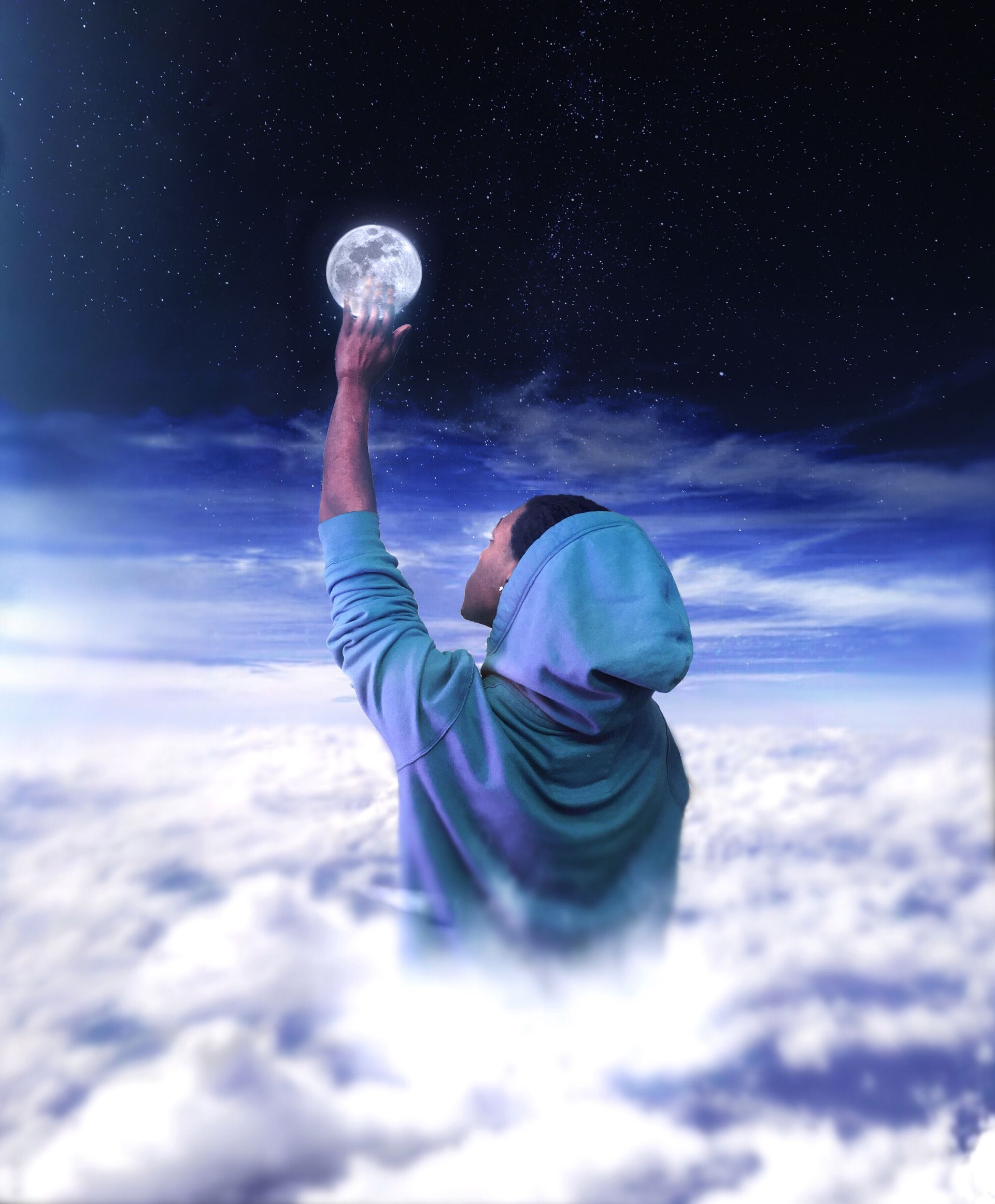 Person in a hooded sweatshirt reaching toward the moon above glowing clouds at night