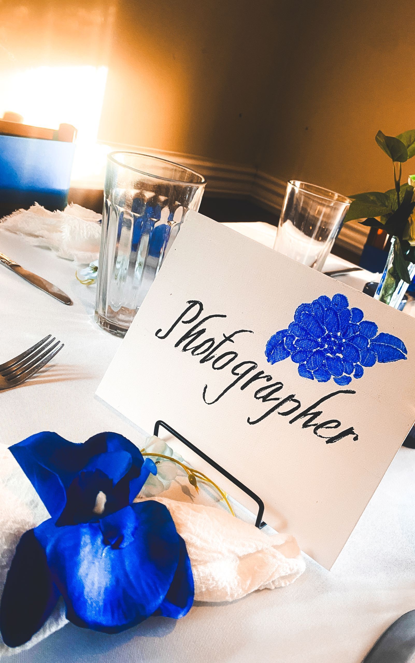 Photo table card with blue flowers and a blue ribbon on a white table setting