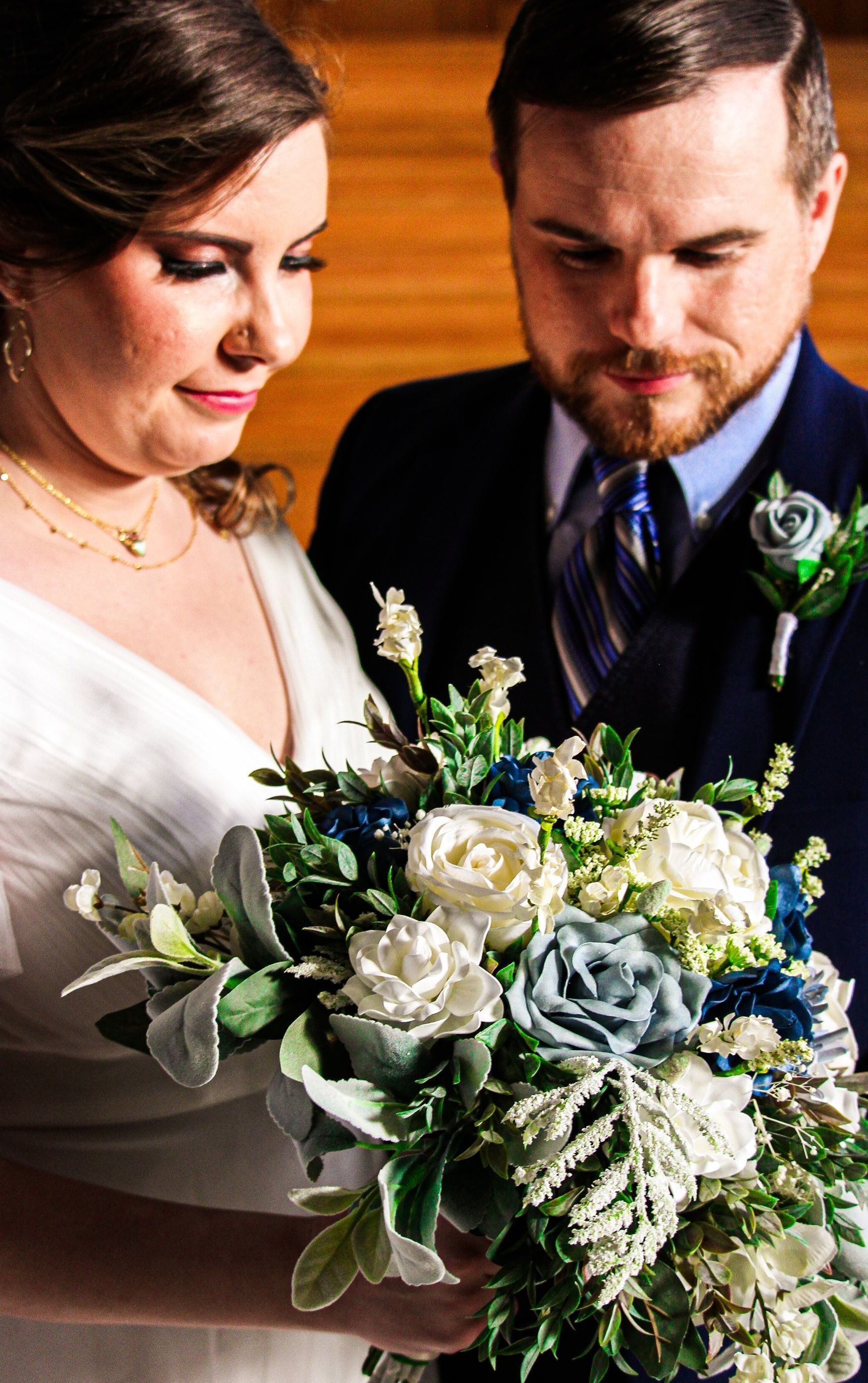 Bride and groom looking at a white and green bouquet during their wedding ceremony