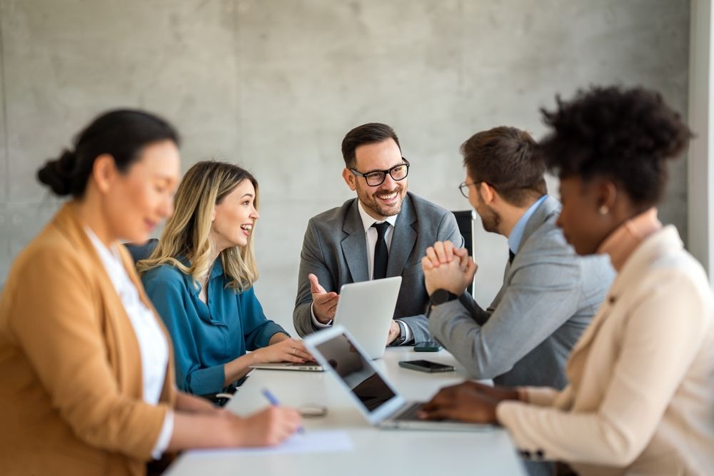 A group of business people are sitting around a table having a meeting.
