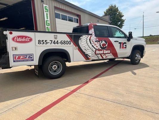 A white and red truck is parked in front of a building