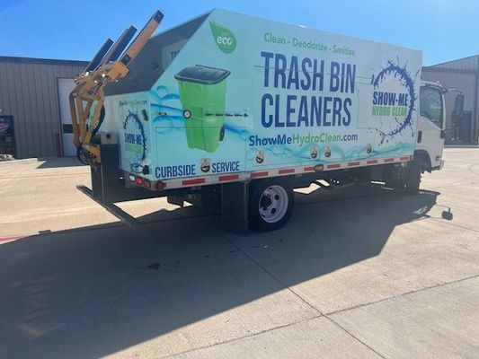A trash bin cleaners truck is parked in a parking lot