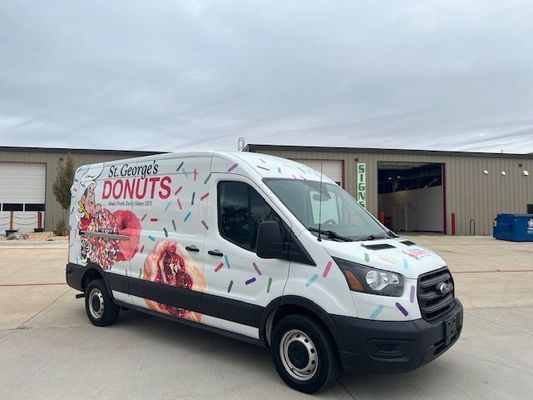 A donut van is parked in front of a building