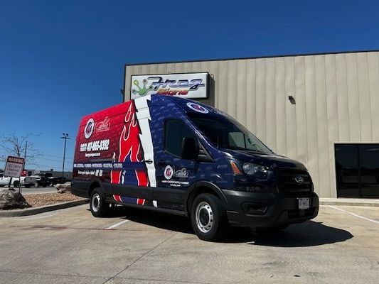 A blue and red van is parked in front of a building