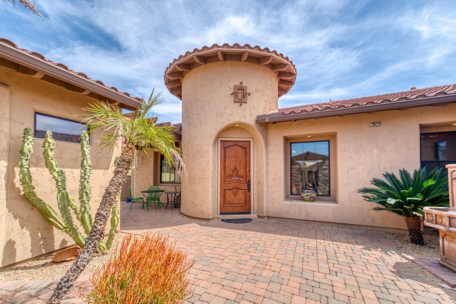 Adobe-style stucco courtyard with arched wooden door, tiled roof, and desert landscaping