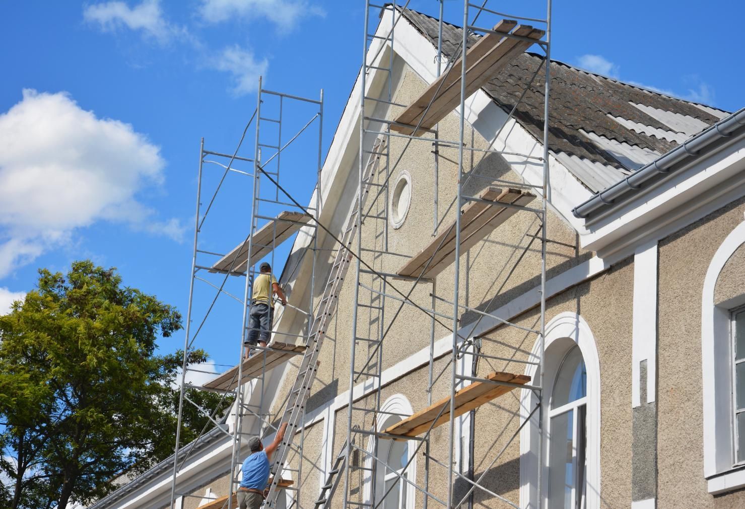 Scaffolding on a church roof under repair against a blue sky