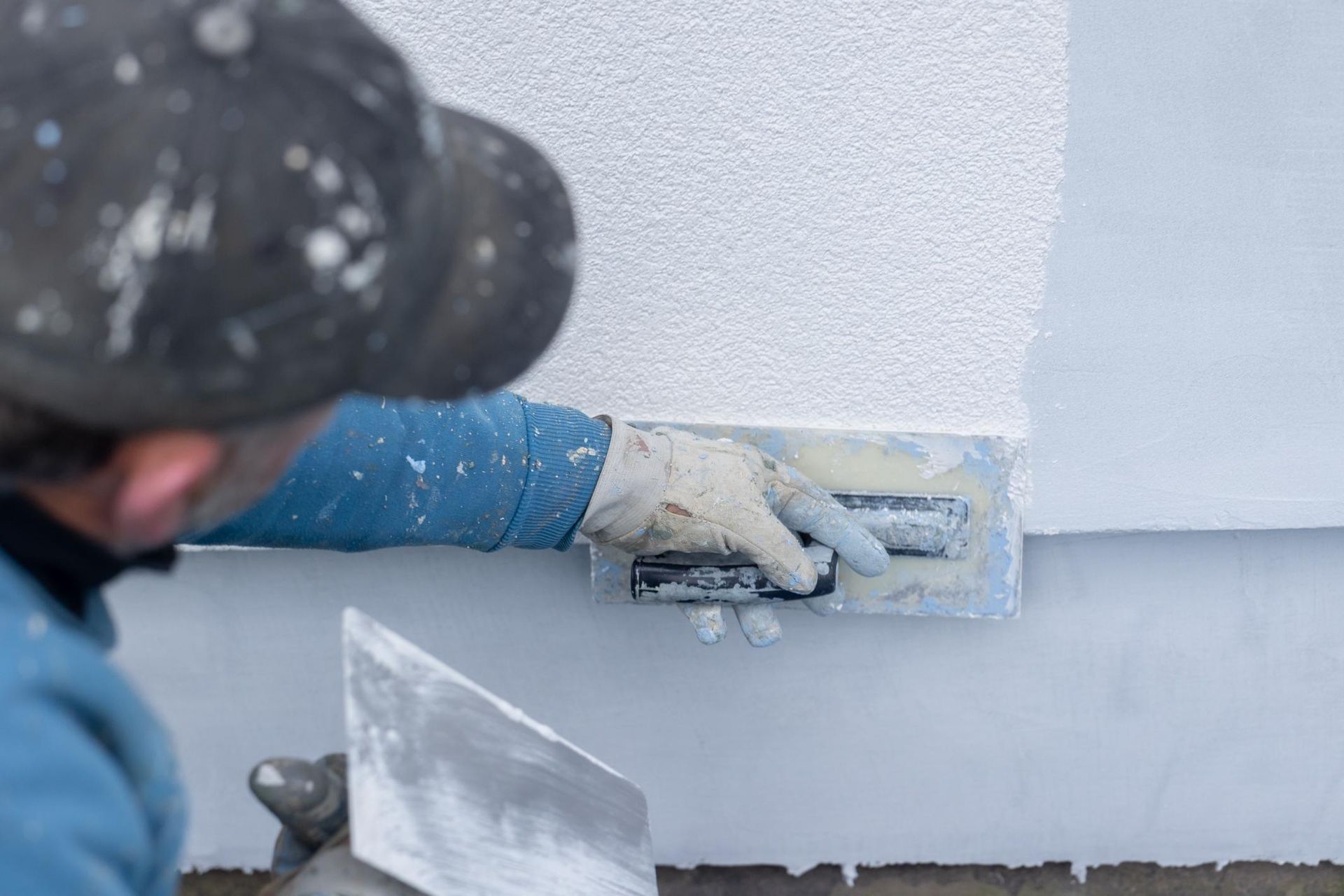 Worker smoothing white plaster on a wall with a trowel