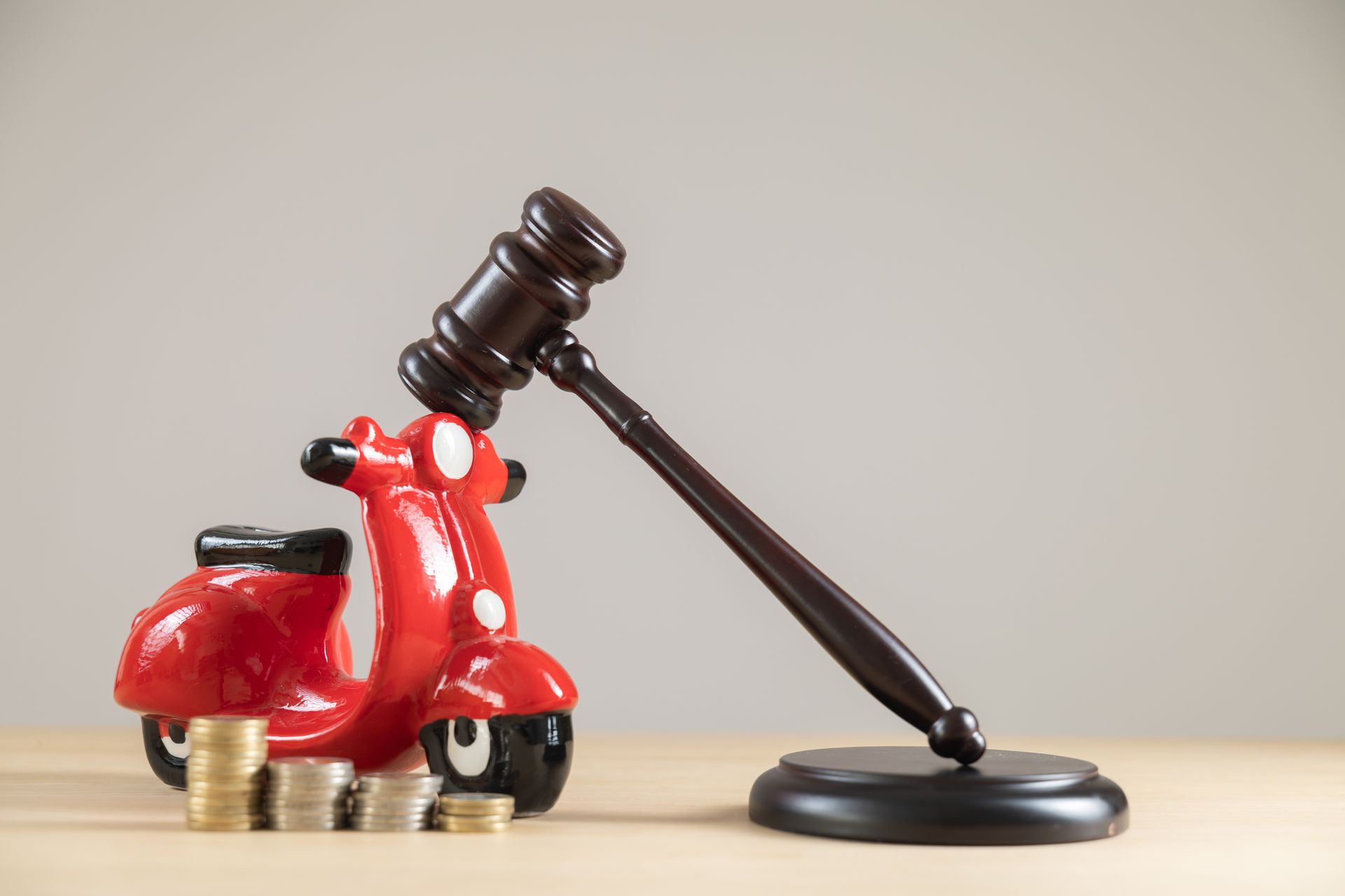 Wooden gavel and red toy motorcycle with stacked coins for a motorcycle accident lawyer