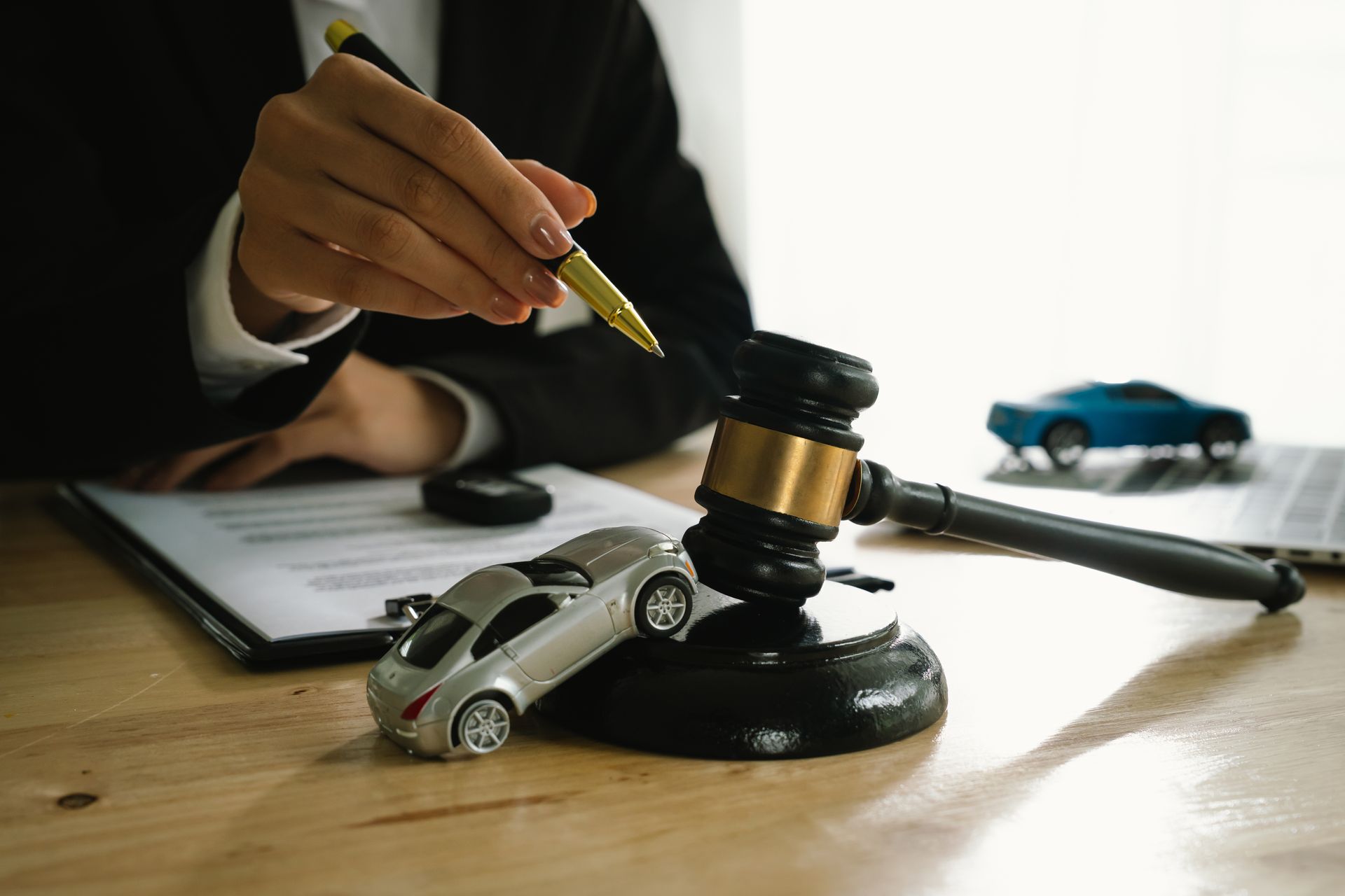 Judge holding gavel over toy cars on a desk, suggesting a legal dispute or auto claim