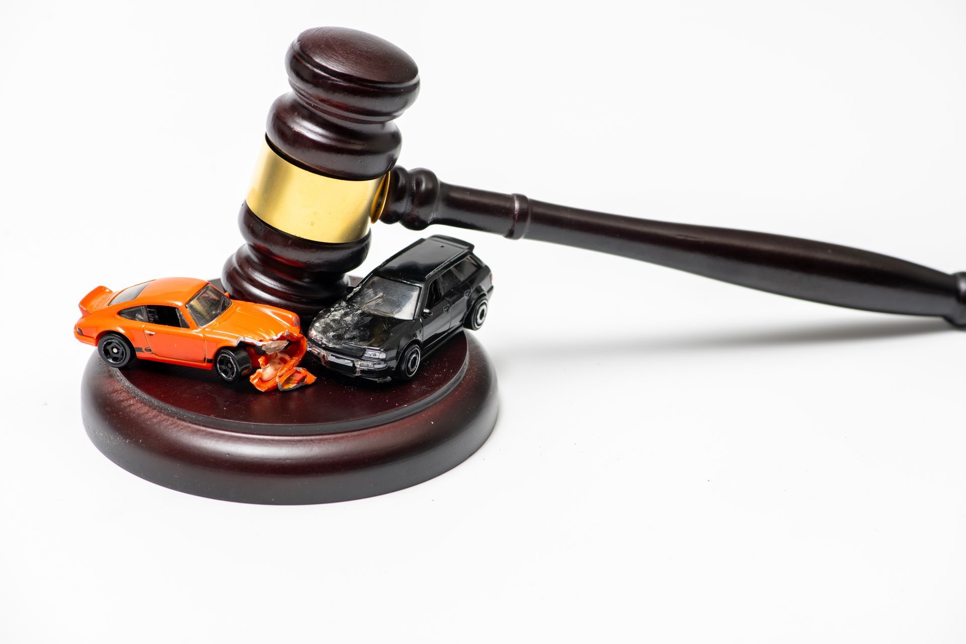 Toy cars crashed together beside a judge's gavel, representing an auto accident lawyer