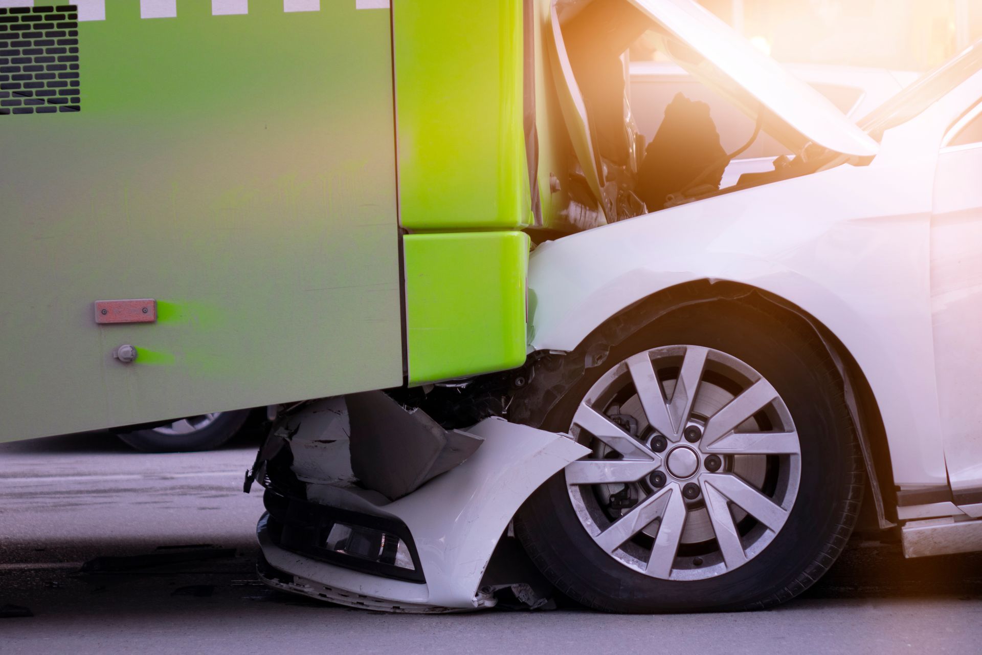 Car crash scene with a green truck hitting the front of a white car, both vehicles damaged.