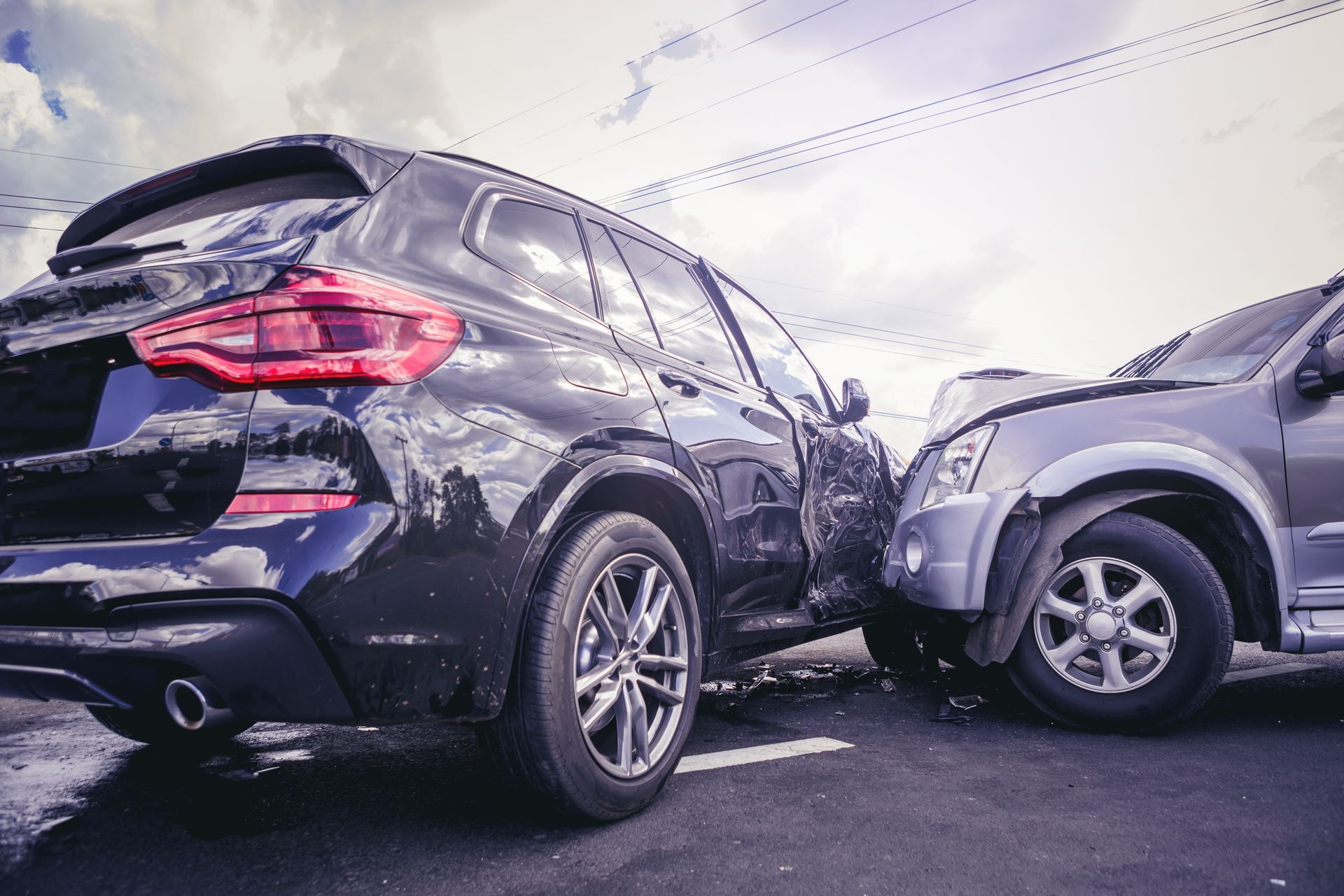 Photograph of a car accident showing a black SUV and a silver SUV with front-end collision damage.