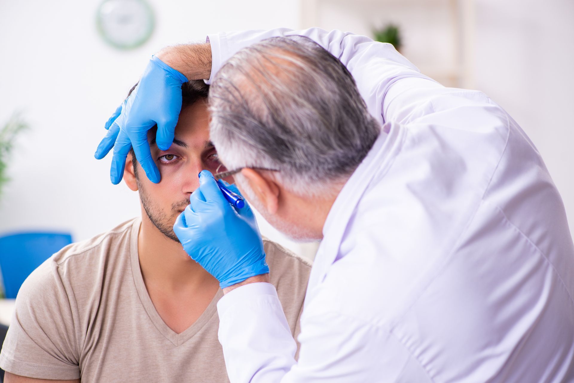 Doctor examining a patient’s eye with blue gloves in a clinic
