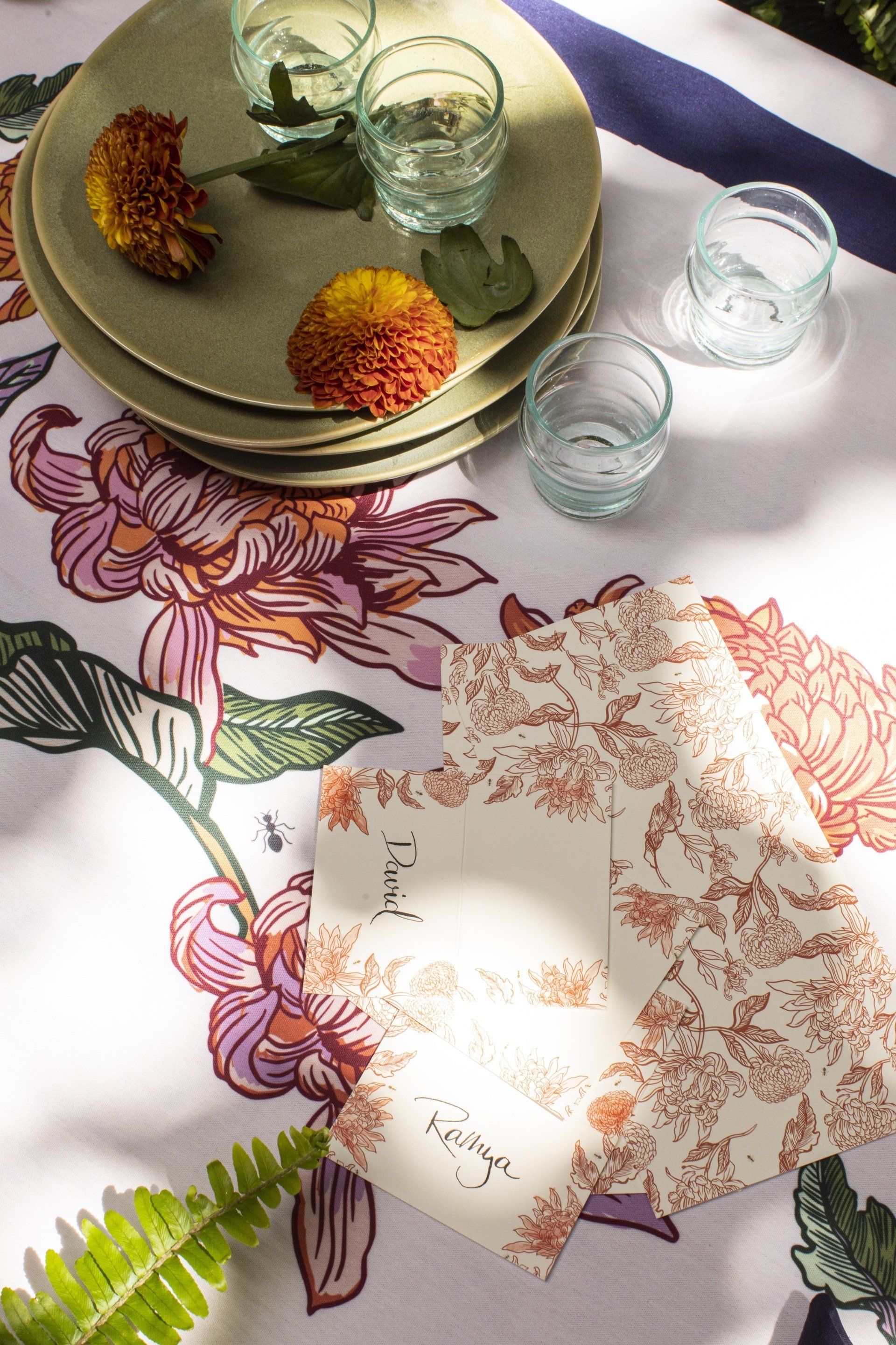 A table with plates , napkins , glasses and flowers on it.