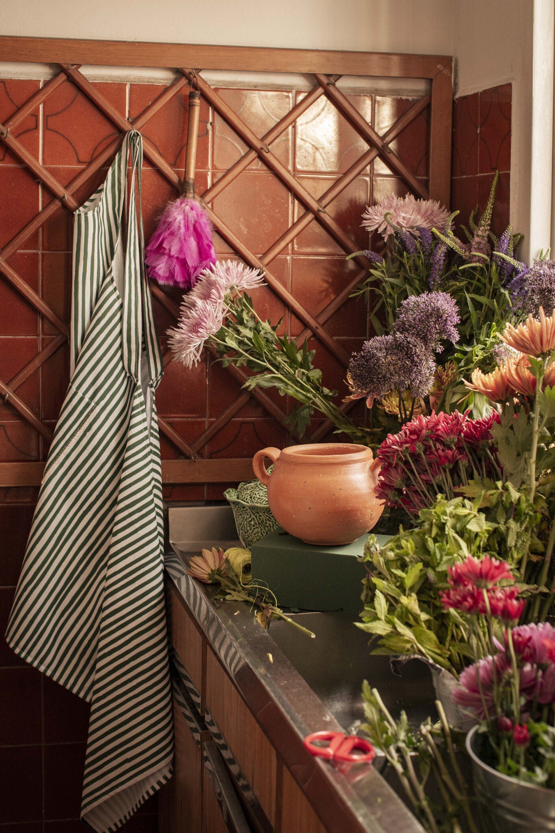 A kitchen sink filled with flowers and a pot.